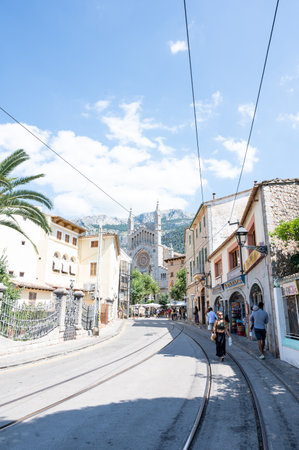 Soller, Spain - June, 19, 2021: Street with the tramway tracks and the village church in the backgroundのeditorial素材