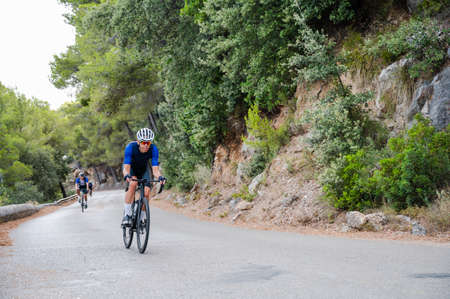 Cyclist in the foreground on a mountain road with another unrecognisable cyclist in the backgroundの写真素材