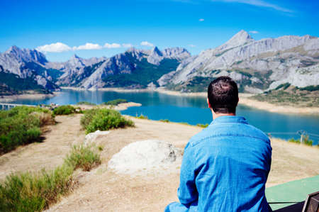 Young man sitting with his back to the mountains of Riano in the Picos de Europaの写真素材