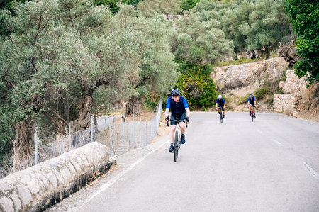 Senior cyclist with two unrecognisable cyclists in the background on a mountain passの写真素材
