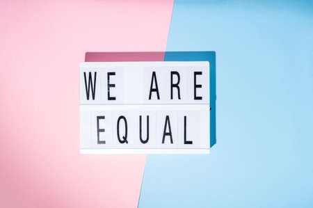 We are equal text on the lightbox. Concept of feminism on a blue and pink background. Top viewの写真素材