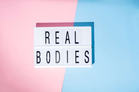 Real Bodies text on the lightbox. Concept of feminism on a blue and pink background. Top viewの写真素材