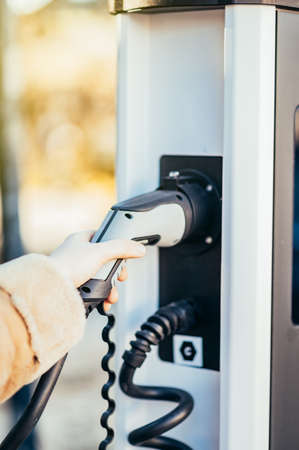 Close-up of an unrecognizable womans hand holding an electric car charger socket. Image with shallow...