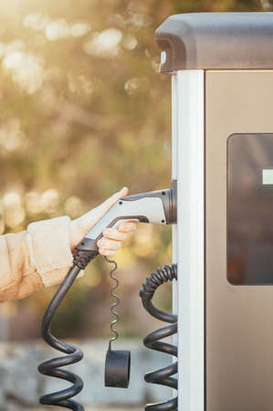 Close-up of an unrecognizable womans hand holding an electric car charger socket. Image with shallow depth of fieldの写真素材