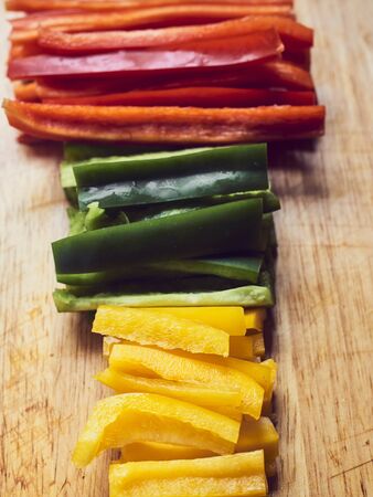 Red Pepper, green pepper and yellow pepper cut on wooden table