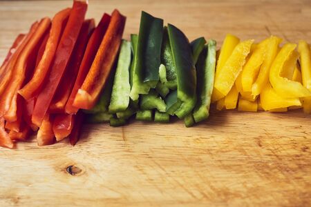 Red Pepper, green pepper and yellow pepper cut on wooden table