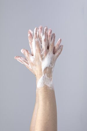White people's hands washing each other with green foamy Marseille's soap isolated in front of a...