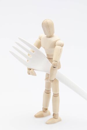 Wooden dummy carrying a biodegradable fork in front of a white backgroundの写真素材