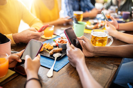 Group of young connected people using mobile phone at terrace bar