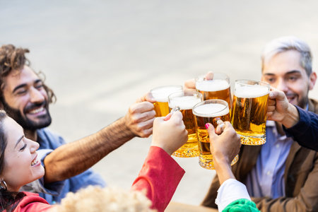 Group of multiracial happy friends cheering with beers at terrace brewery bar
