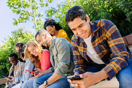 Young group of people using cell phones sitting together outside.
