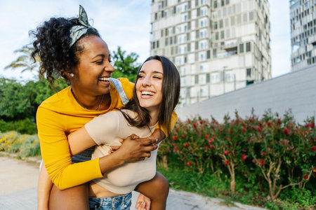 Couple of young women in love piggybacking in city streetの写真素材