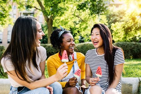 Cheerful multiethnic group of female friends talking and having fun togetherの写真素材