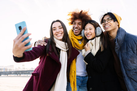 Young happy group of teenage friends taking a selfie portrait on winter day
