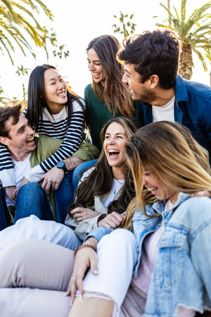 Vertical photo of happy group of millennial friends having fun sitting outdoorsの写真素材