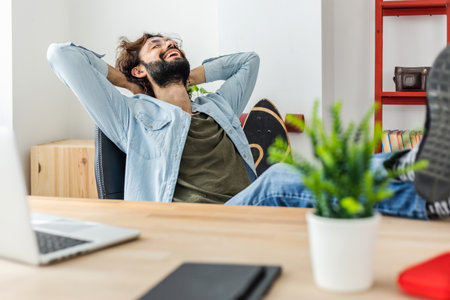 Happy relaxed man celebrating the end of the working day in the officeの写真素材