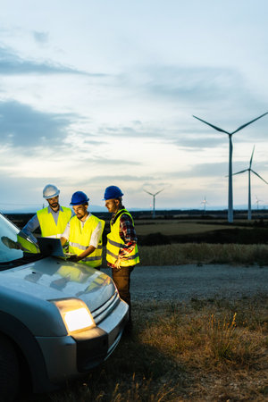 Engineers teamwork discussing renewable energy project at wind turbine farmの写真素材