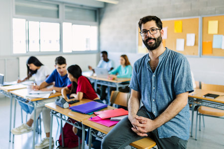 Portrait of young bearded male teacher sitting at high school table