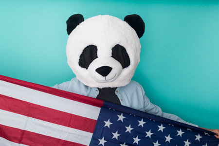 Happy unrecognizable man holding american flag while standing against blue background. 4th of july...