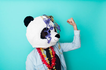 Excited man in panda mask with party ornaments celebrating on colored backgroundの写真素材