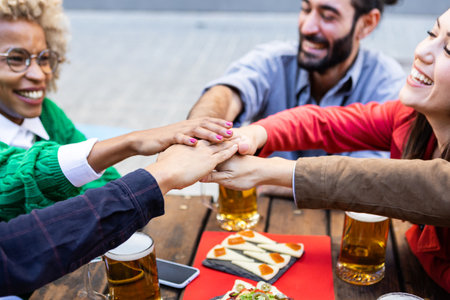 United multiracial group of young students stacking hands at brewery bar
