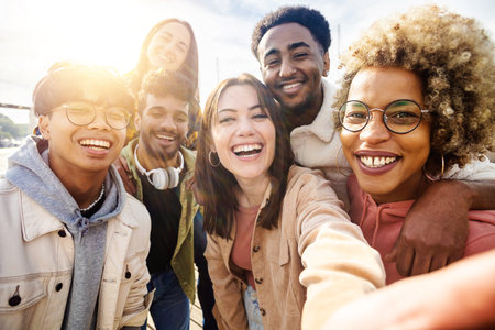 Happy young friends having fun while taking a selfie with mobile phone outdoorsの写真素材