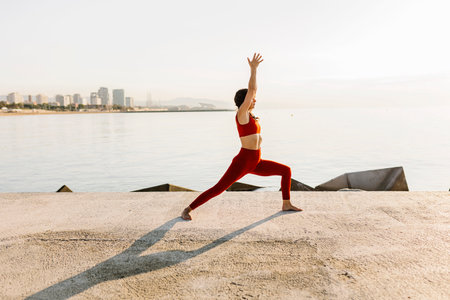 Hispanic mid adult woman doing yoga and meditating - Warrior yoga poseの写真素材