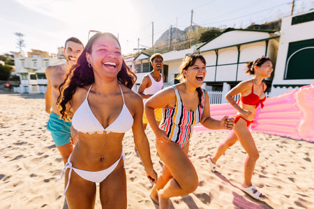 Happy young friends enjoying summer vacation running together at beachの写真素材
