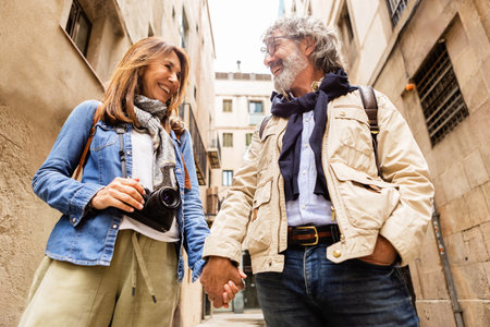 Lovely senior pensioner couple holding hands standing in city streetの写真素材