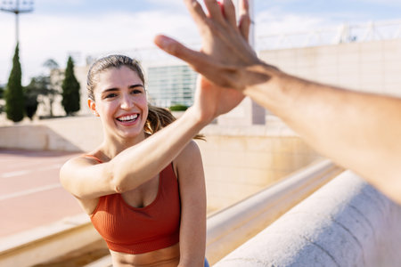 Portrait of beautiful fit young woman giving high five to unrecognizable personの写真素材