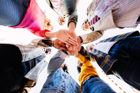 United young group of diverse people joining hands outdoors