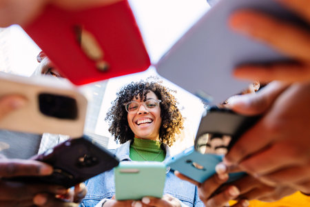 Happy group of young people using mobile phones outdoors.
