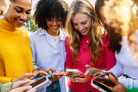 Young group of multiracial women using mobile phones together outdoor