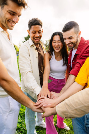 Multiracial young happy friends stacking hands at city parkの写真素材