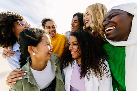 Seven happy young adult women from different cultures laughing together outdoorsの写真素材