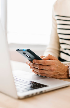 Close-up view of woman hands using cell phone device at office workplace