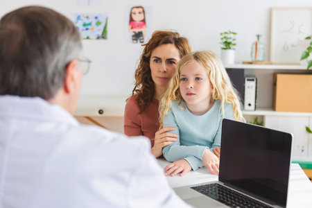 Young adult mother visiting pediatrician doctor with her little sick daughterの写真素材