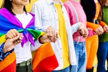Young group of LGBT people holding hands outdoors showing support and unity.