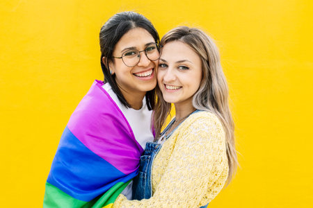 Portrait of lovely young lesbian couple hugging each other smiling at cameraの写真素材