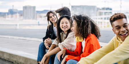 Young group of happy students sitting together outside while hanging outの写真素材