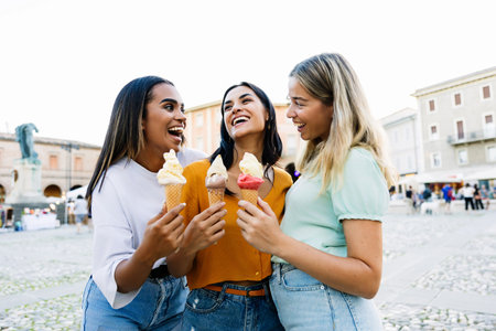 Three pretty multiracial happy women eating ice cream during summer vacationの写真素材
