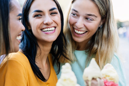 Three young tourist women eating ice cream together at city streetの写真素材