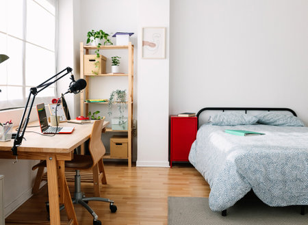 Cozy mood. Interior bright teen room with bed and creative workplace deskの写真素材