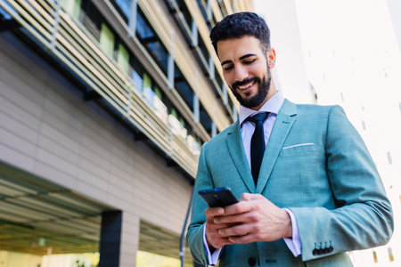 Businessman in formal suit using cellphone standing outside building officeの写真素材