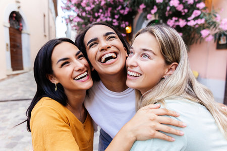 Portrait of three young multiracial women laughing together outsideの写真素材