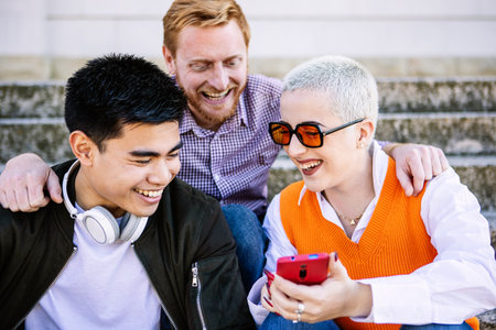Three multiracial young friends having fun watching media content on phone app