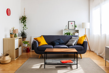 Interior of bright living room with cozy sofa, wooden shelves and houseplantsの写真素材
