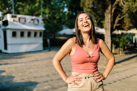Cheerful trendy woman smiling outdoors - Happy young female standing with arms on waist in the street - Happiness and youth conceptの写真素材