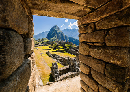 View of Machu Picchu on a sunny day through the frame of stone wallの写真素材