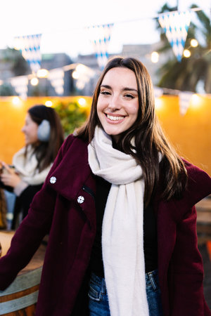 Young woman in warm clothes smiling at camera standing outdoors on winterの写真素材